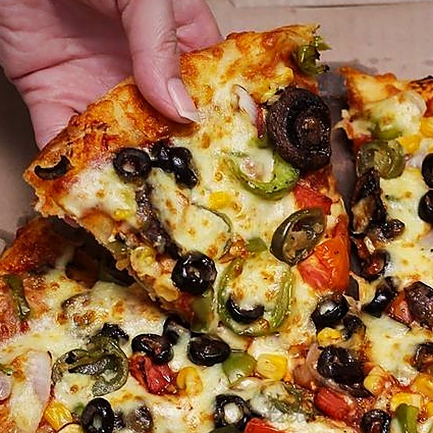 Trozo de pizza levantándose con queso fundido, aceitunas y champiñones